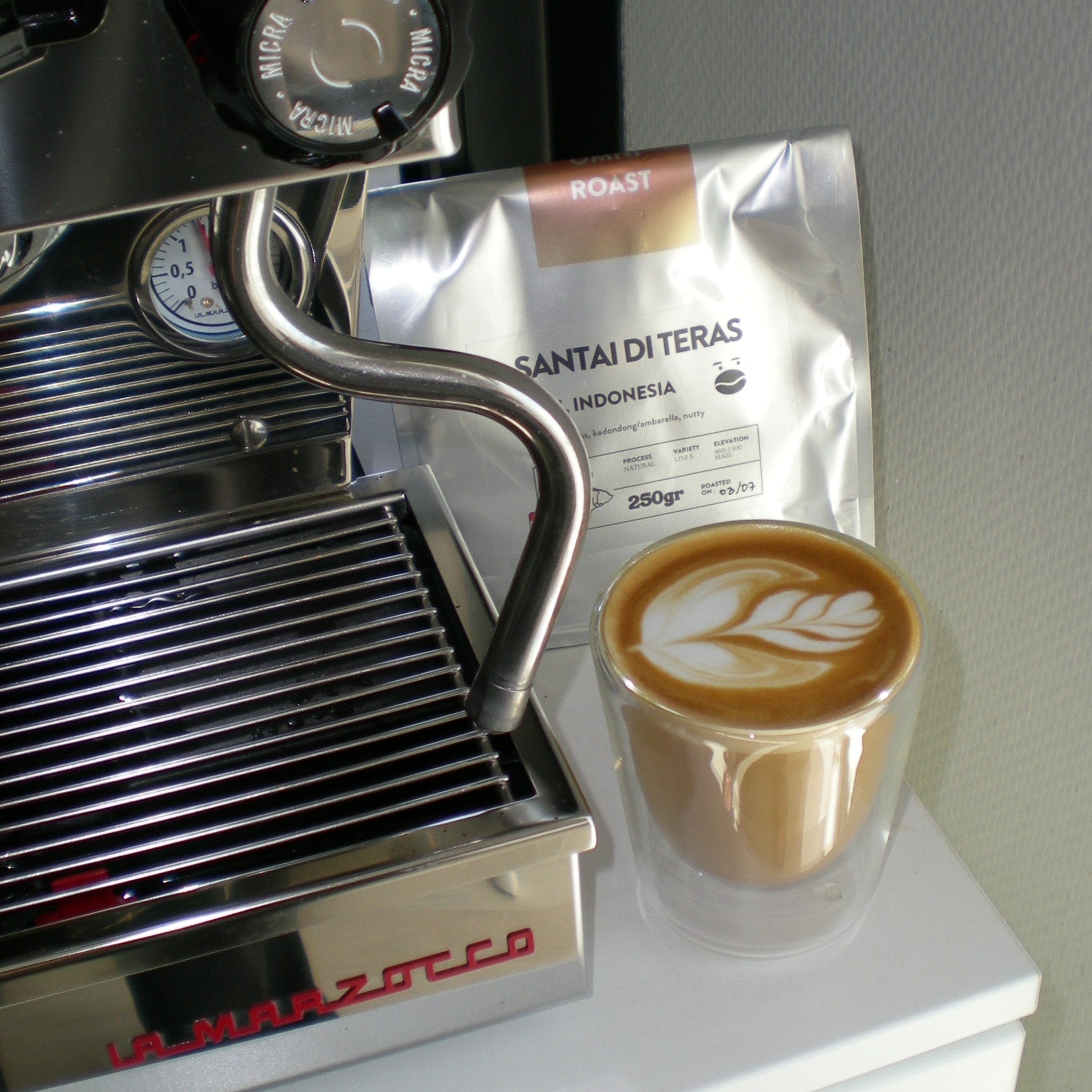 Espresso machine with a cup of coffee and a bag of coffee beans on a white surface.